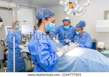 Surgeon writing on clipboard in operation room