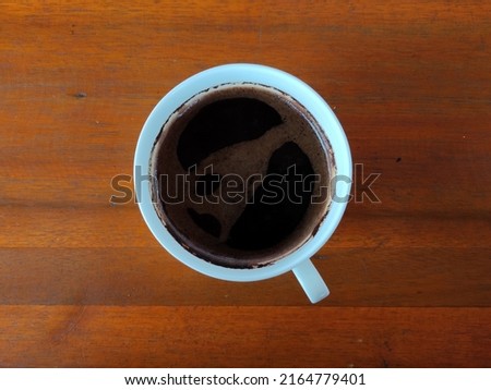 a cup of warm black coffee on a wooden table