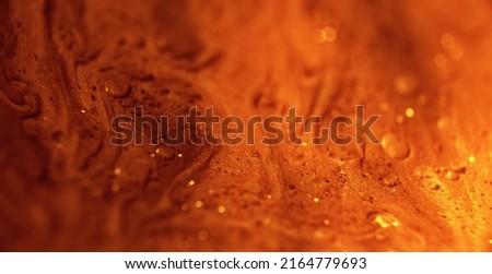 Glitter paint flow. Molten gold texture. Floating ink. Defocused yellow orange sparkling fluid motion. Abstract art background shot on RED Cinema camera. Royalty-Free Stock Photo #2164779693