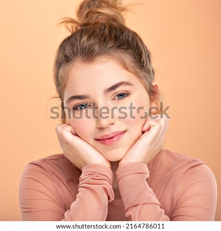 Closeup portrait of an young  girl over colored background.  Photo of a fashion model posing at studio. Pretty young woman with  brown hair looking at camera. Beauty portrait. 