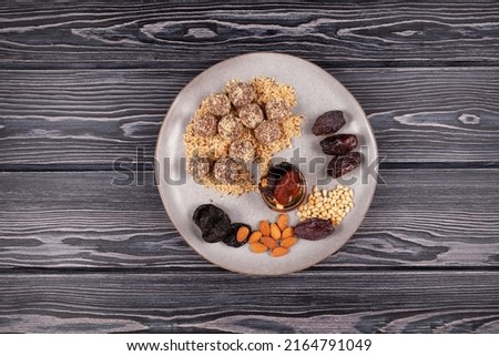 Energy balls or Healthy homemade sweets in plate on dark wooden background, top view. Healthy bites made of ground dried fruit and nuts. Energy balls are a healthy snack.