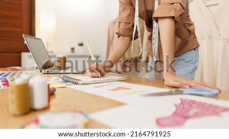 Fashion design concept, Asian female fashion designer sketching new clothes collection in atelier.