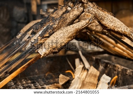 Trout skewered on a wooden stick grill over an open fire