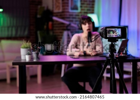 Content creator vlogging lifestyle podcast episode on camera, using live broadcasting equipment in studio. Female vlogger recording online talk show conversation, web livestream. Royalty-Free Stock Photo #2164807465