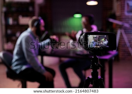 Multiethnic team of people meeting to broadcast internet podcast, recording video discussion on camera. Influencer and guest talking on online livestream to create social media channel content. Royalty-Free Stock Photo #2164807483