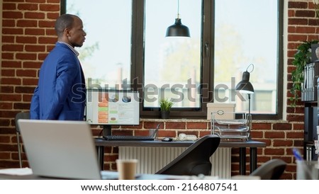 African american consultant waiting in company office to receive good business news. Nervous project manager pacing around startup workplace to find out about presentation solution. Royalty-Free Stock Photo #2164807541