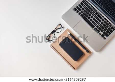 Laptop, phone, notepad and glasses, top view