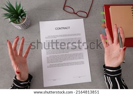 Femal hand gestures show that she is unhappy with terms of suspicious contract. Woman disagrees with bad contract terms, refuses to sign document. 