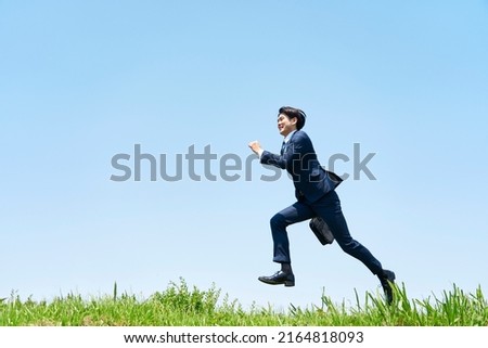 Asian businessman running under the clear sky Royalty-Free Stock Photo #2164818093