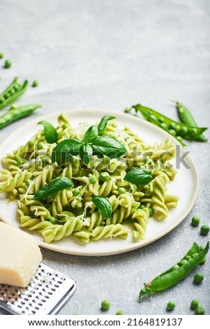 Green peas pasta. Rotini pasta with fresh green peas sauce and basil served on plate.