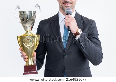happy mature man in suit hold champion cup and microphone isolated on white background