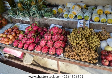 street market view with fresh fruits sale: pineapple, mango, apple, dragon fruit, longan, tropical vitamins  