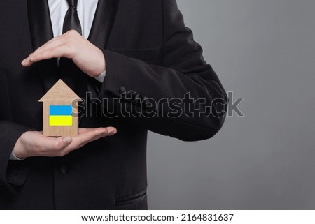 Man holding house with Ukrainian flag in his hands