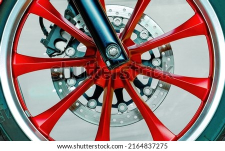 Wheel of modern motorcycle. Spokes, brake disc, pads. Close-up. Red, black, chrome color