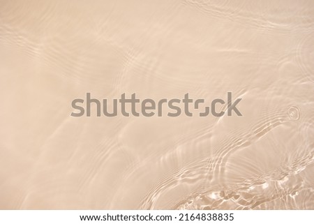 Transparent beige clear water surface texture with ripples, splashes. Abstract nature background Water waves in sunlight with copy space, top view. Cosmetic moisturizer micellar toner emulsion Royalty-Free Stock Photo #2164838835