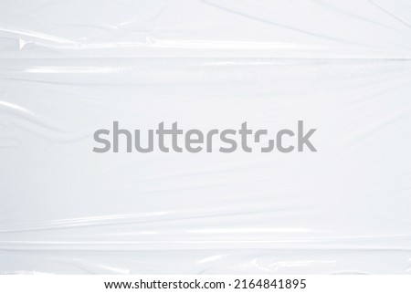 Transparent plastic wrap on white color background. Crumpled wrinkled plastic cellophane. Reflecting light and shadow on creases and folds in plastic surface. Texture overlay effect template Royalty-Free Stock Photo #2164841895
