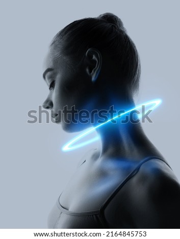 Contemporary design. Young sad woman with blue neon circle around her neck isolated over light grey background. Concept of beauty, digital fashion style, creativity, digitalization, technology era
