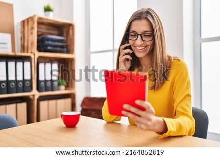 Young woman business worker talking on the smartphone using touchpad at office