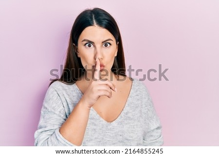 Young hispanic woman wearing casual clothes asking to be quiet with finger on lips. silence and secret concept. 