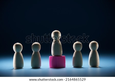 Wooden figures as a group and red figurine as leader