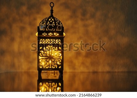  Ornamental Arabic lantern with burning candle glowing at night.