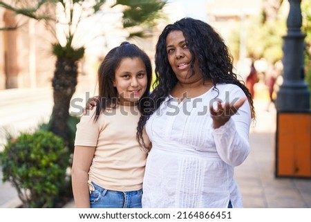Mother and daughter standing together speaking at park