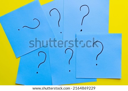 top view of question marks written on blue cards on yellow background