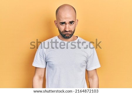 Young bald man wearing casual white t shirt depressed and worry for distress, crying angry and afraid. sad expression.  Royalty-Free Stock Photo #2164872103