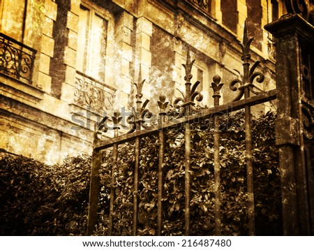 Typical Parisian building with forging gate and colorful firethorn bushes. Autumn in Paris. Retro aged photo with scratches. Sepia.