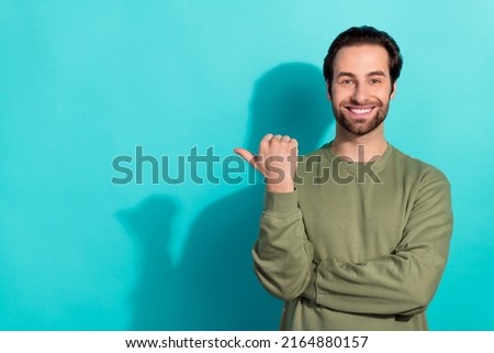 Photo of funky brunet young guy index empty space wear green shirt isolated on teal color background