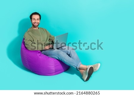 Full size profile side photo of young guy purple beanbag use laptop manager isolated over turquoise color background