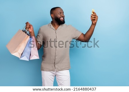 Portrait of positive nice handsome guy hold packages telephone make selfie isolated on blue color background