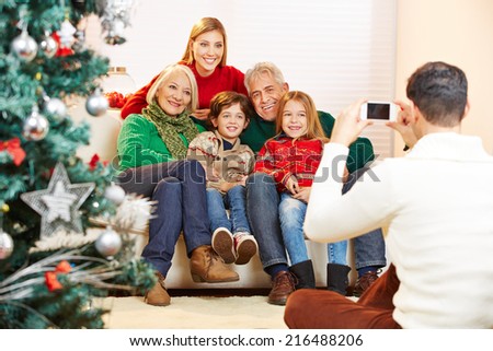 Father taking family picture at christmas with his smartphone