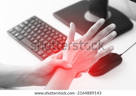 Young woman working in office with a carpal tunnel syndrome or wrist joint inflammation Royalty-Free Stock Photo #2164889143