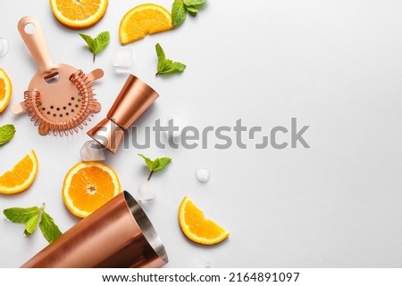 Copper strainer, double jigger, cobbler shaker and cocktail ingredients on grey background Royalty-Free Stock Photo #2164891097