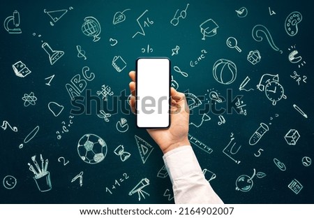 School icons set drawing on chalkboard and hand holding smartphone with blank screen for websites or mobile applications. Back to school concept. Hand drawn background with school supplies