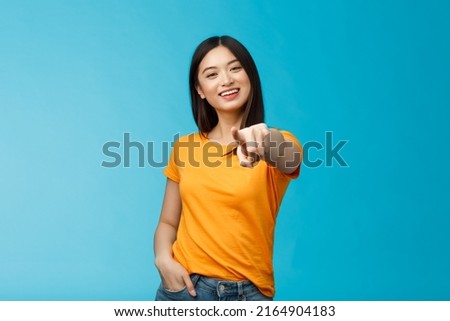 Lucky winner. Cheerful charismatic asian cute urban girl stand yellow t-shirt smiling friendly pointing finger camera choosing, picking person, inviting you team, stand happy blue background Royalty-Free Stock Photo #2164904183