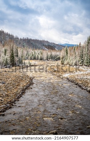 The not frozen bed of a beautiful winding Chibit River flowing through a snow-covered valley surrounded by mountains of Altai, Siberia, Russia. High quality photo