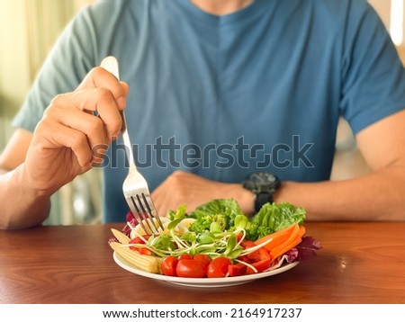 Man's hand scooping green salad. Healthy lifestyle and vegetarian vegan concept, Intermittent Fasting. Royalty-Free Stock Photo #2164917237