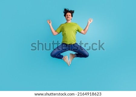 Full length photo of dreamy attractive man wear green t-shirt practicing yoga jumping high isolated blue color background