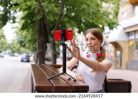 a young woman blogs while sitting outside in the summer
