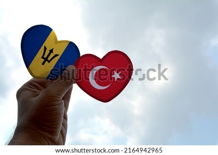 Hand holds a heart Shape Barbados and Turkey flag, love between two countries