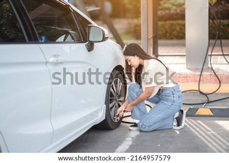 Asian woman inflating tires at the gas station with a self-service automatic  Royalty-Free Stock Photo #2164957579