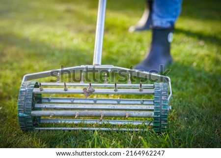 Picture of grass aerator on the green lawn Royalty-Free Stock Photo #2164962247
