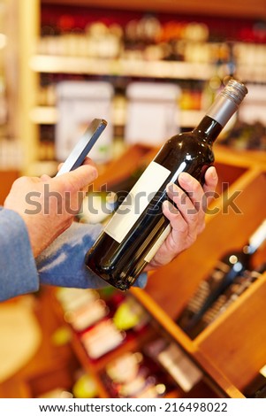 Price comparison with app in smartphone on bottle of red wine