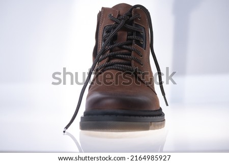 Men's winter boot made of genuine leather and natural fur on a light background.