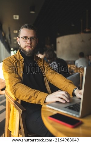 The guy programmer works in a cafe. The guy works remotely in a cafe. Distance learning. Programmer. Hipster.