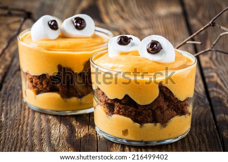 Halloween treats, little monster dessert with chocolate cookies and orange mascarpone cream  topped with big marshmallow eyes Royalty-Free Stock Photo #216499402