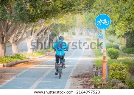 Cyclist ride along a bike path in a park with painted pavement and road signs. Eco-friendly transport infrastructure in the city and safety