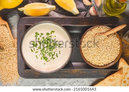 Arabic Cuisine; Egyptian traditional Tahini Sauce with sesame seeds, fresh lemon and olive oil. Top view with close up. Royalty-Free Stock Photo #2165001643